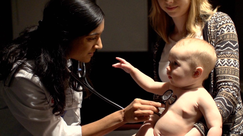 Welcome Home campaign still: a clinician examining a baby alongside a parent